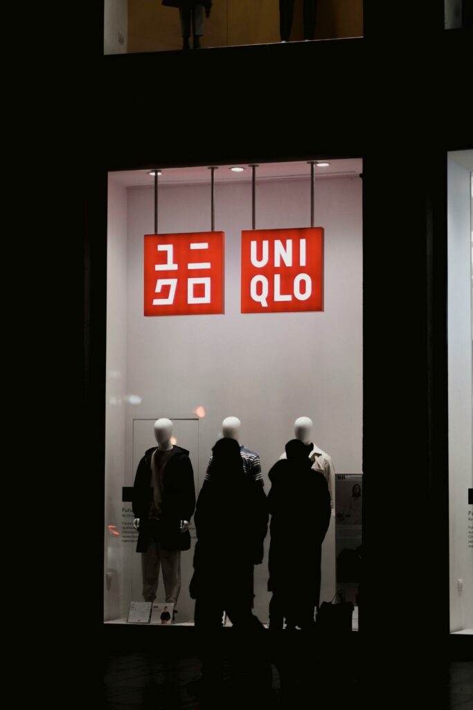 Nighttime view of a Uniqlo store display with mannequins in urban setting.